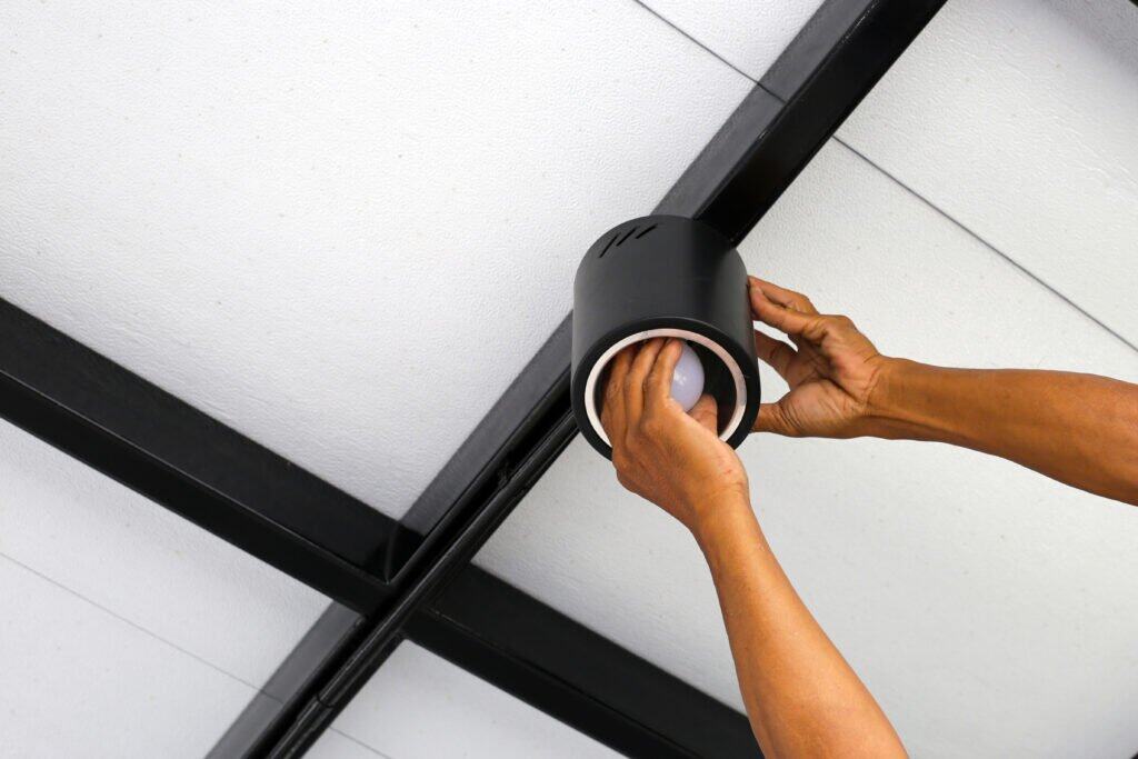 Hands of an electrician installing a light on the ceiling. Energiezuinige LED-verlichting wordt geïnstalleerd in het plafond.